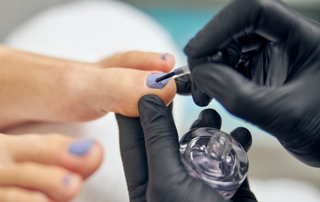 Beautician doing pedicure with gel polish for client