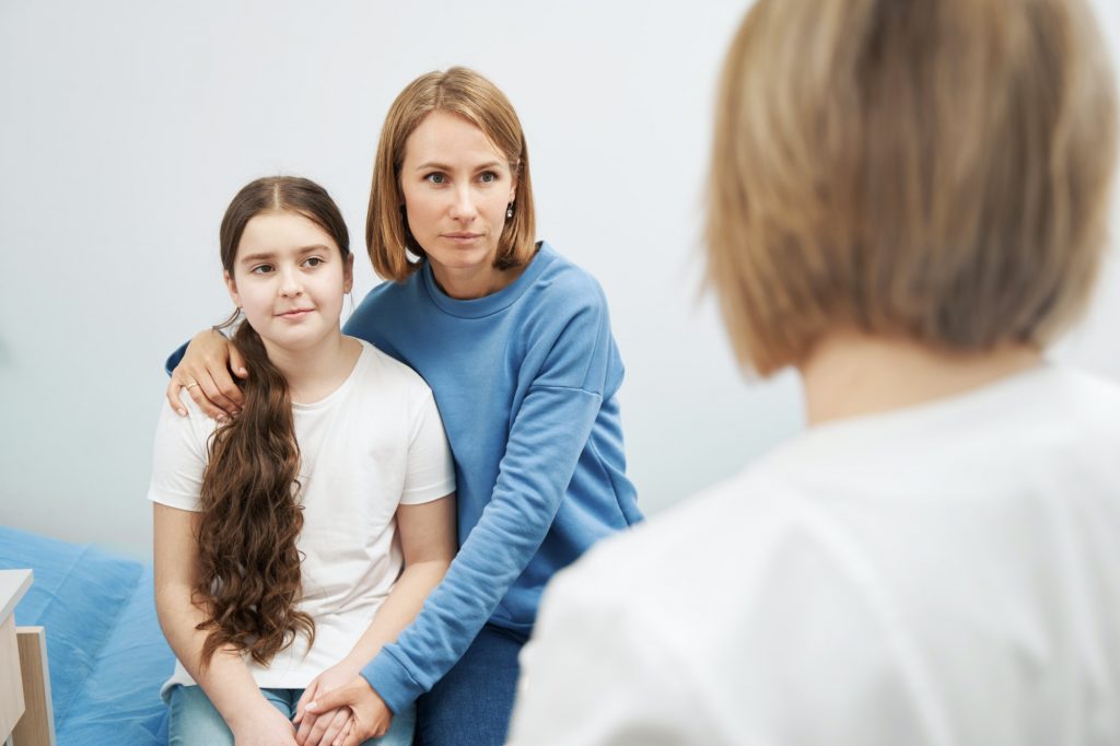Woman and little girl having appointment with doctor in clinic